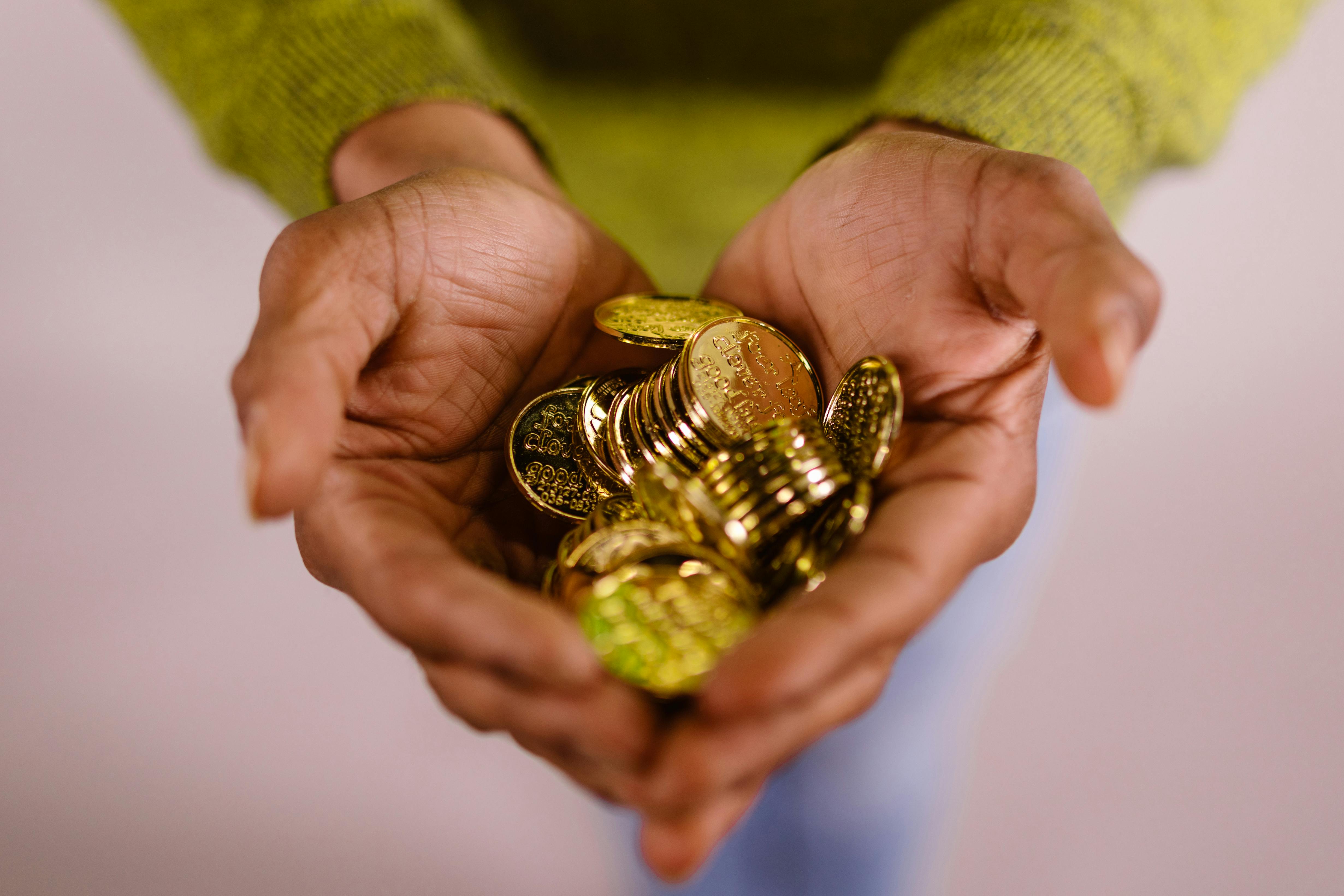 hands holding pile of gold coins