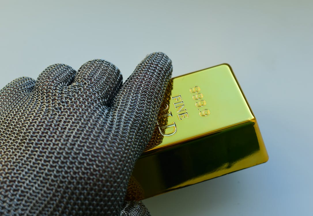 gloved hand holding a gold bar