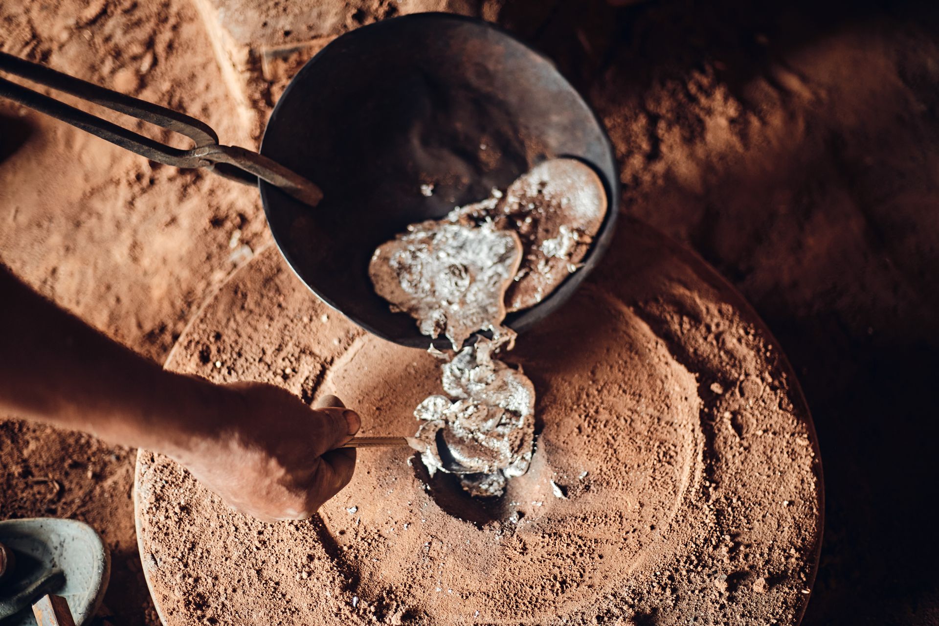 Worker pouring silver into a furnace for refining.