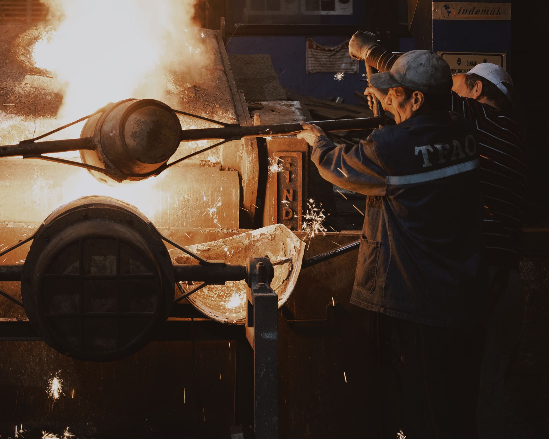 Workers operating a furnace and crucible in an industrial refinery.