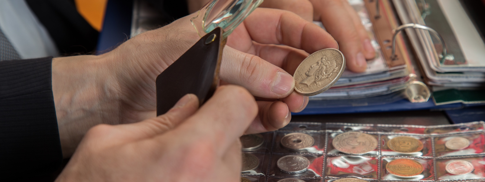 coin collector inspecting rare coin with magnifying glass