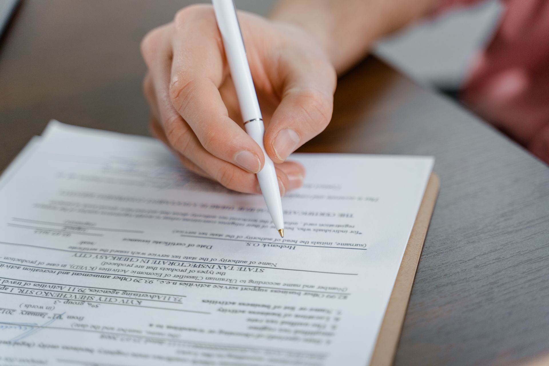 Someone filling out a tax form on a clipboard.